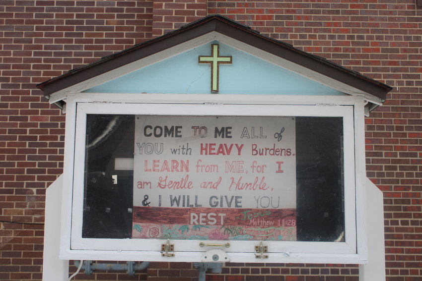 A handwrtitten sign outside of The Rising quoting the bible: "Come to me all of you with heavy burdens. Learn from me. For I am gentle and humble. I will give you rest" -Jesus, Matthew 11:28.